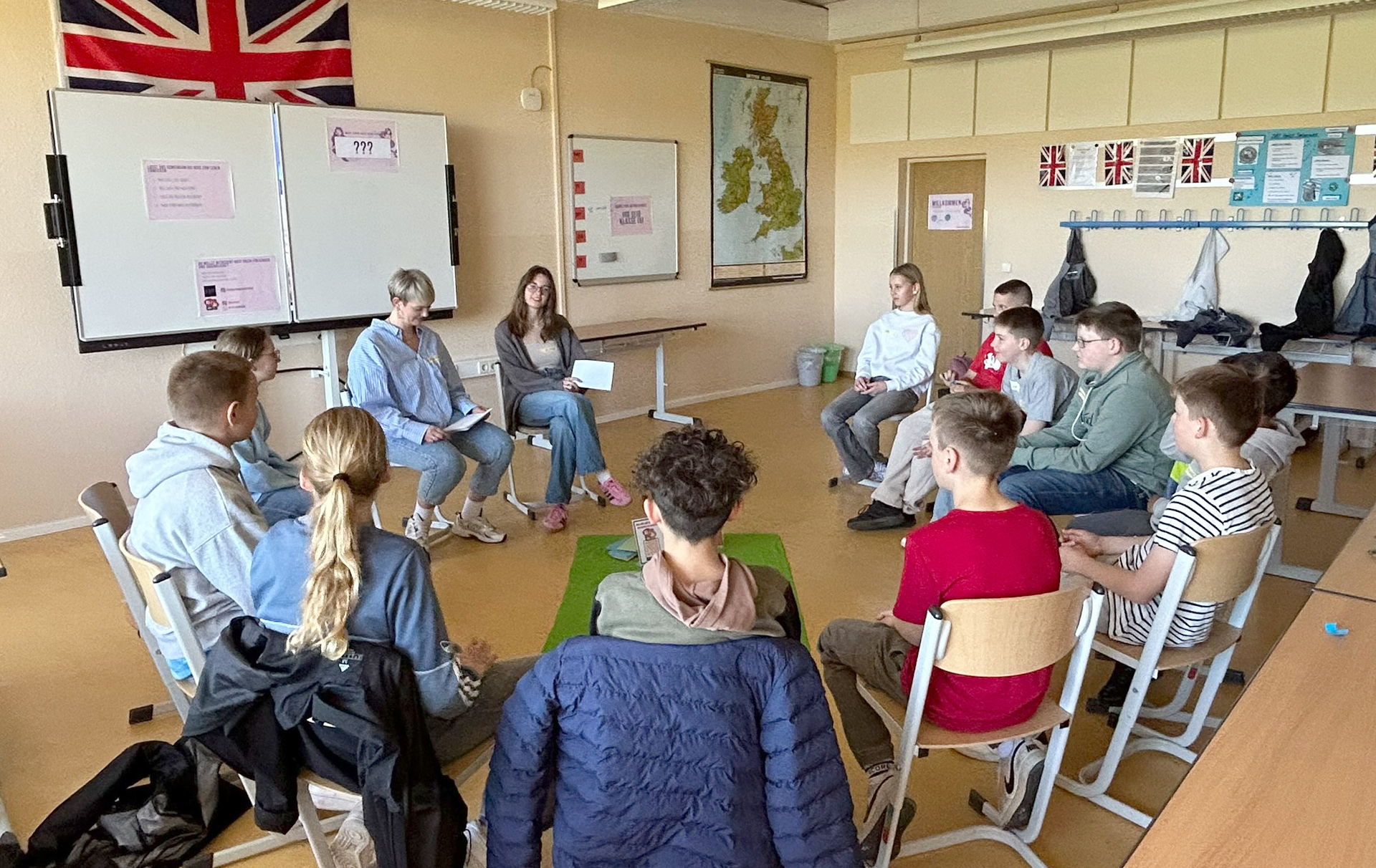 Foto: Gruppe sitzt im Kreis in einem Klassenraum
