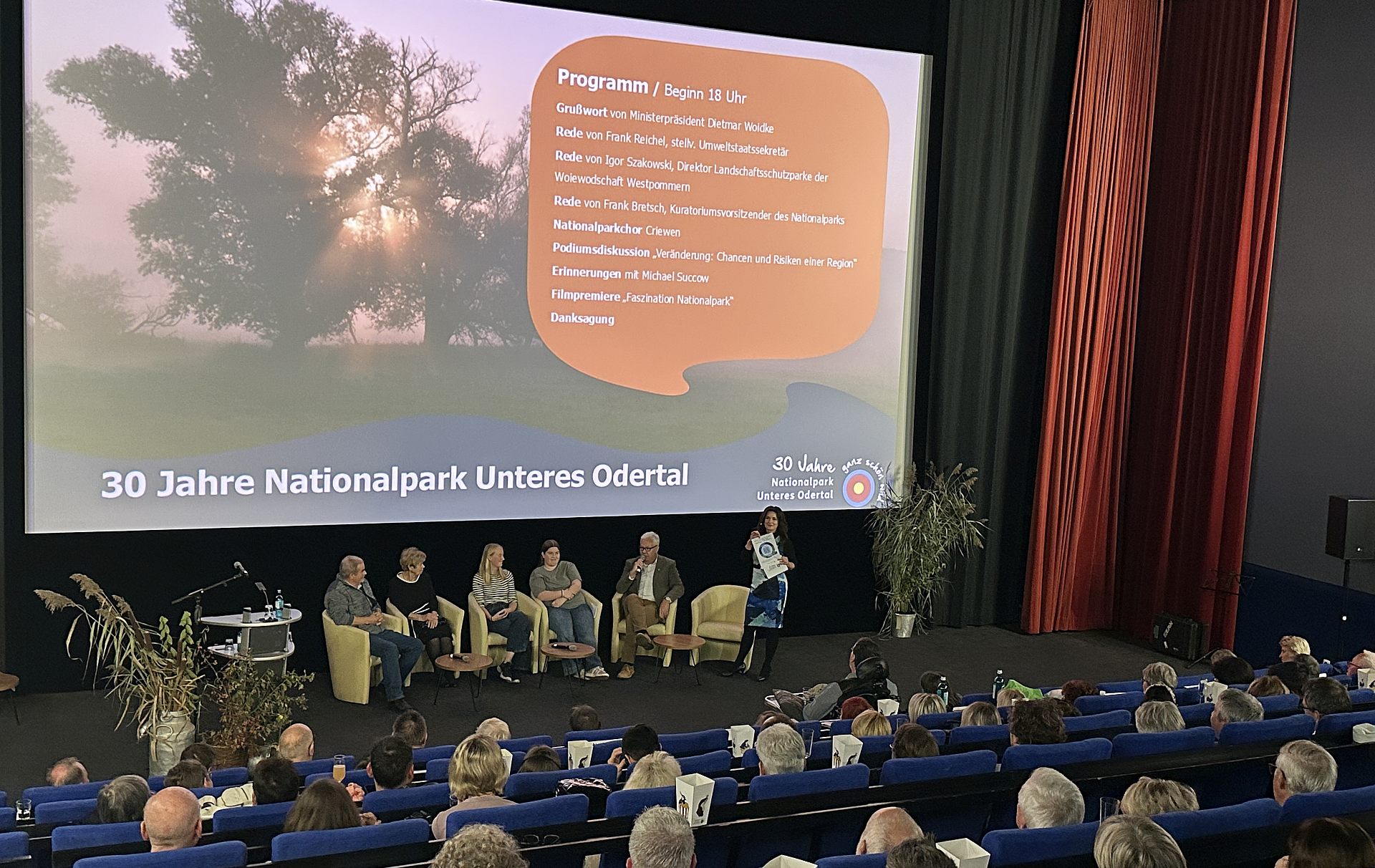Foto: Kinosaal mit Publikum und einer Podiumsdiskussion vor der Leinweind Foto: Kinosaal mit Publikum und einer Podiumsdiskussion vor der Leinweind