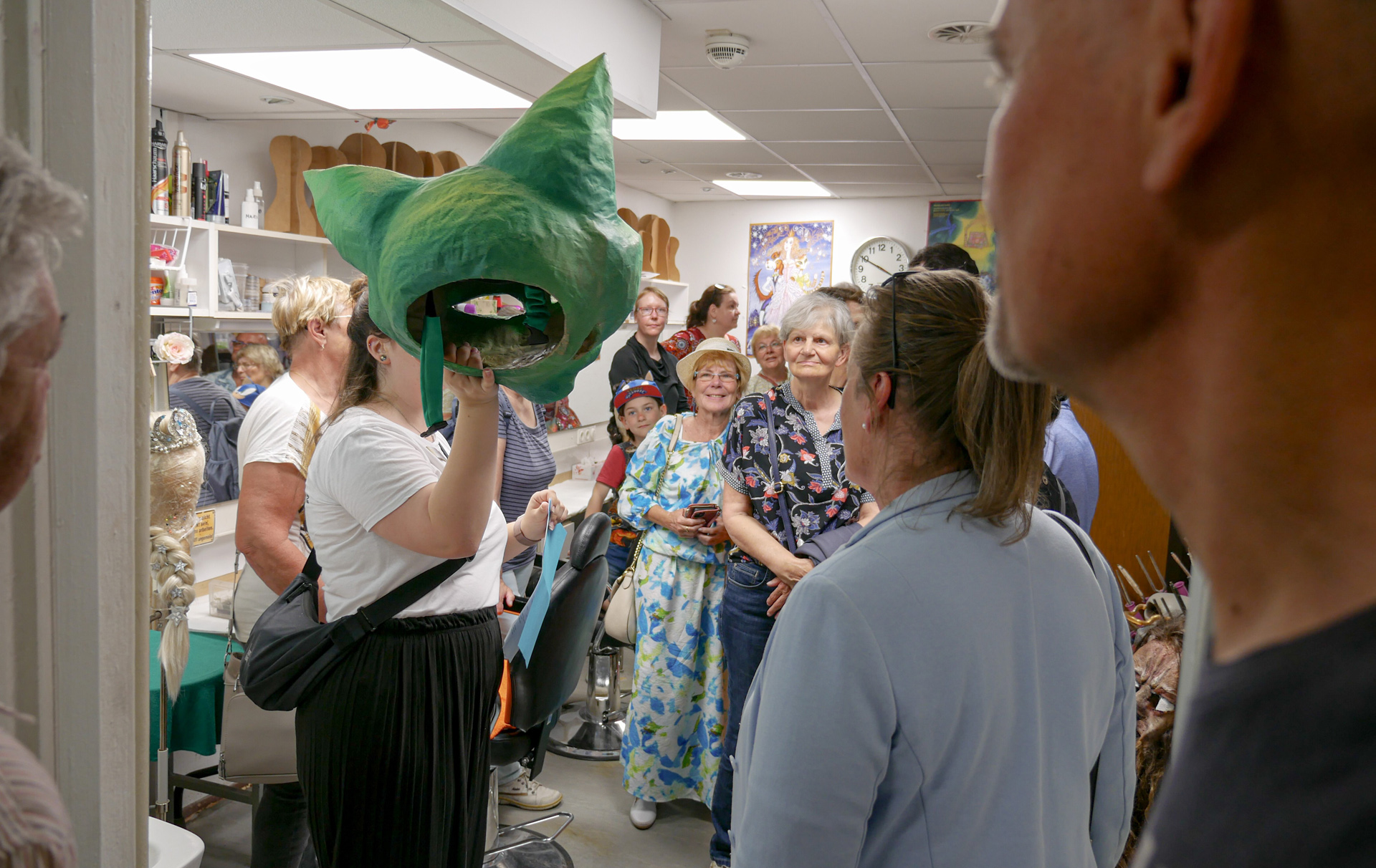 Foto: Frau zeigt mehreren Zuschauern eine grüne Tiermaske