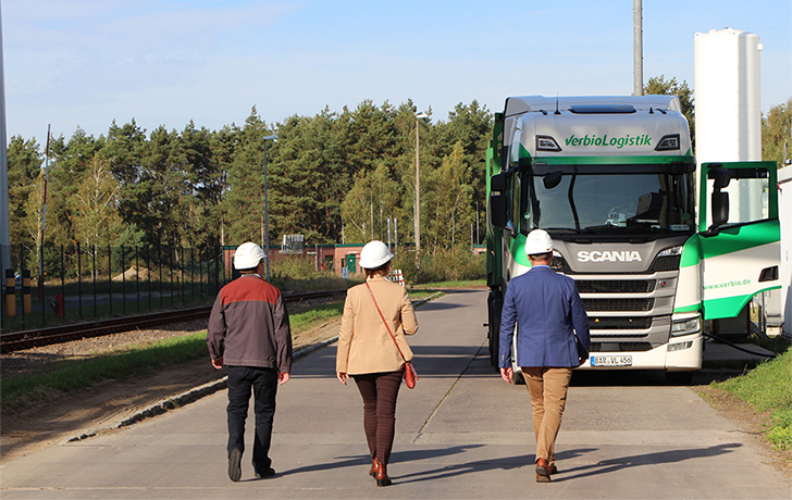 Foto: 3 Personen mit Helm gehen auf eine LKW zu Foto: 3 Personen mit Helm gehen auf eine LKW zu