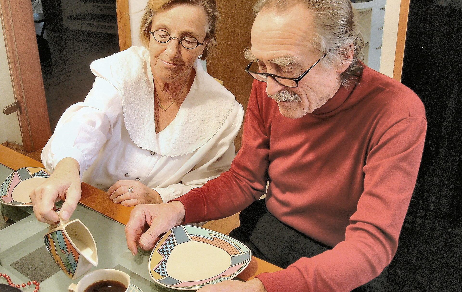 Foto: Frau gießt einem alten Mann Milch in den Kaffee Foto: Frau gießt einem alten Mann Milch in den Kaffee
