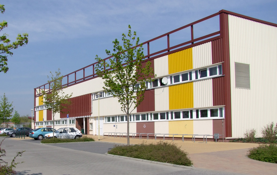 Foto: Eingangsbereich der Sporthalle mit parkenden Autos davor Foto: Eingangsbereich der Sporthalle mit parkenden Autos davor