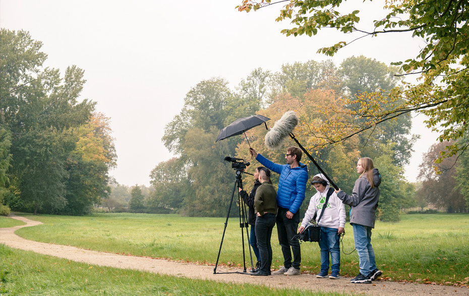 Foto: Gruppe beim Filmen mit Stativ, Kamera, Mikrofon, Aufnahmetasche und Schirm n einer Parklandschaft Foto: Gruppe beim Filmen mit Stativ, Kamera, Mikrofon, Aufnahmetasche und Schirm n einer Parklandschaft