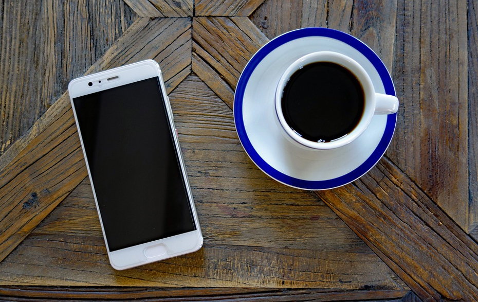 Foto: Handy und Kaffeetasse auf einem Holztisch Foto: Handy und Kaffeetasse auf einem Holztisch