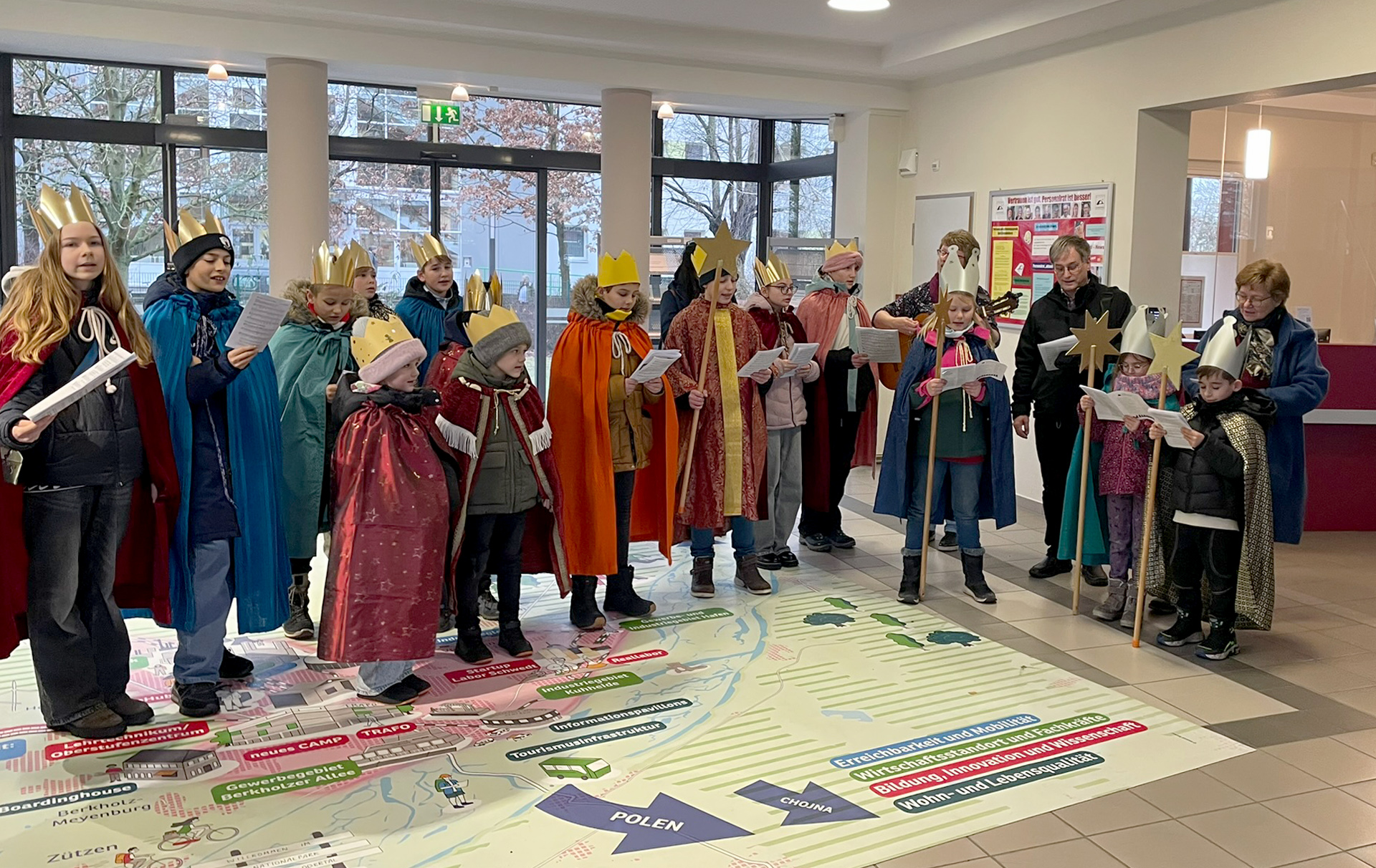 Foto: Gruppe singender Kinder mit goldenen Kronen im Rathausfoyer