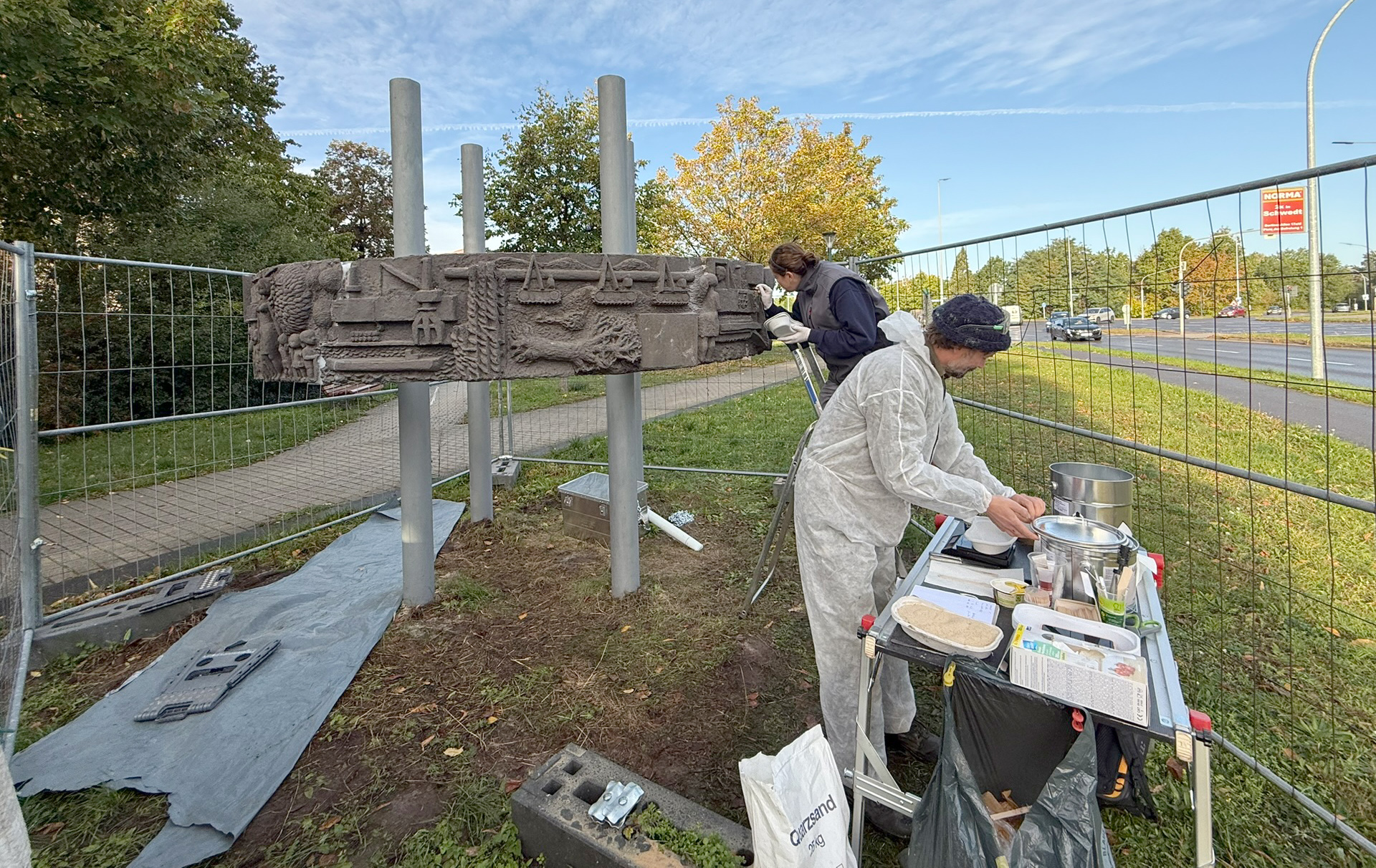 Foto: zwei Personen an und vor der Stele Foto: zwei Personen an und vor der Stele