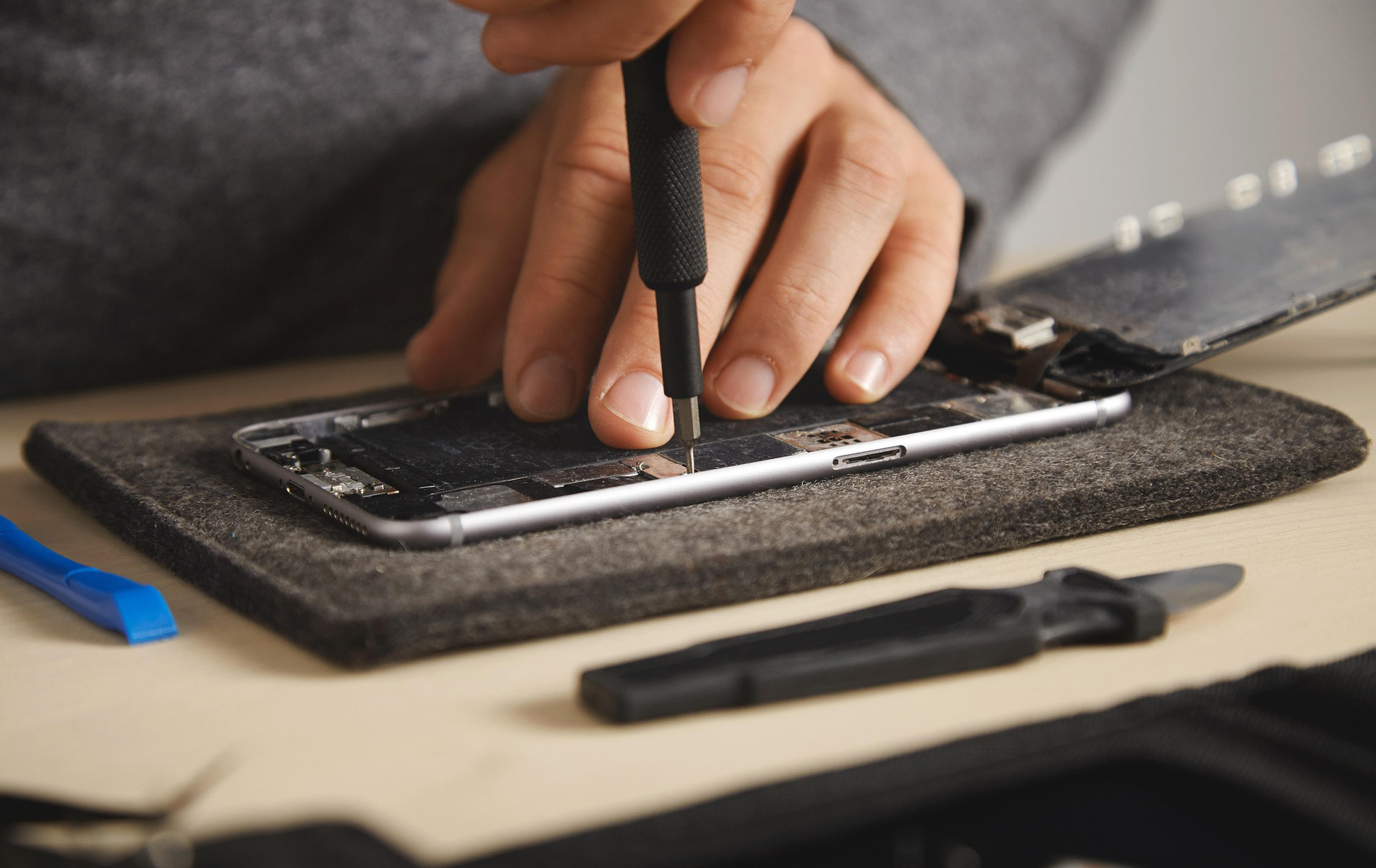 Foto: Hand mit Schraubendreher im Innern eines Smartphones Foto: Hand mit Schraubendreher im Innern eines Smartphones