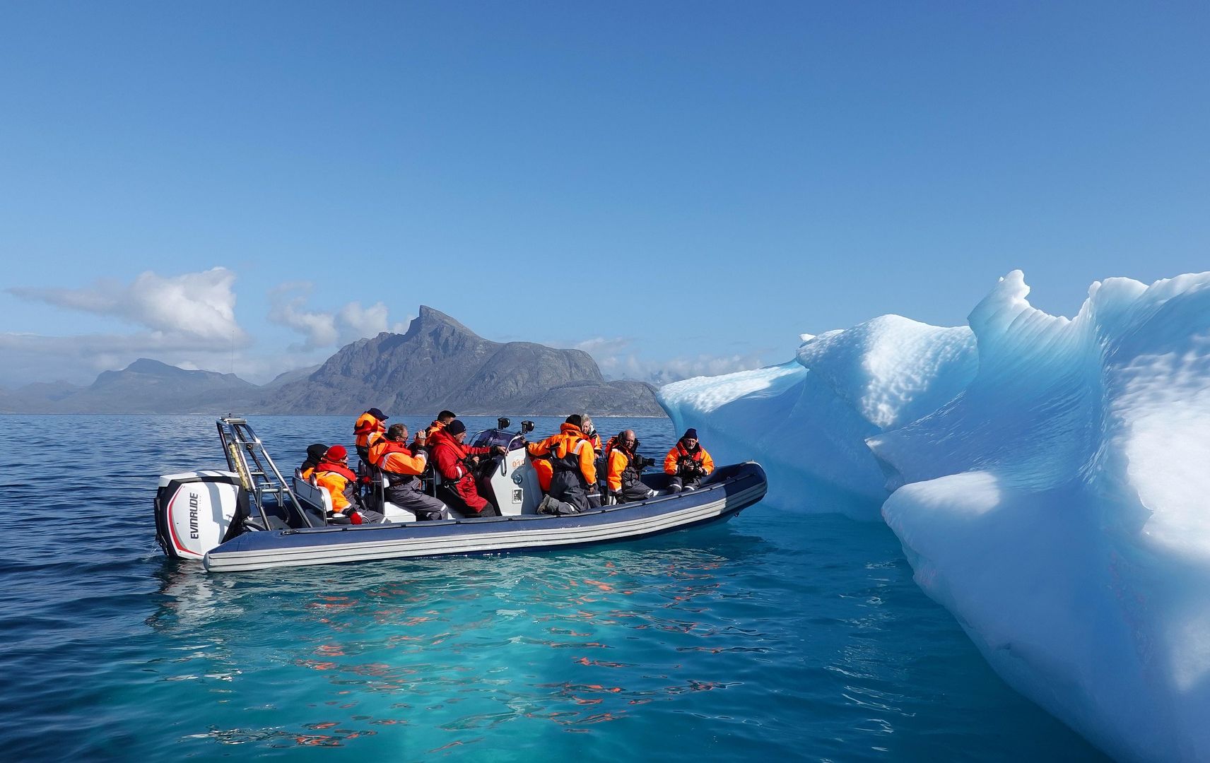 Foto: Boot mit mehreren Personen nähert sich einem Eisberg Foto: Boot mit mehreren Personen nähert sich einem Eisberg