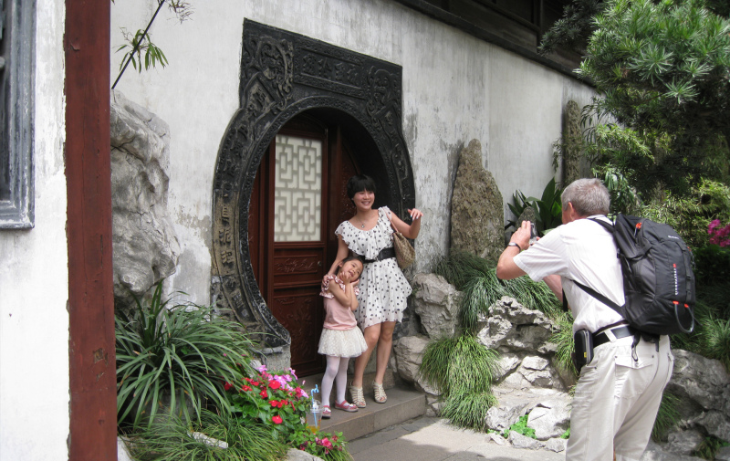 Foto: Mann fotografiert chinesische Mutter mit Kind vor einem Hauseingang Foto: Mann fotografiert chinesische Mutter mit Kind vor einem Hauseingang
